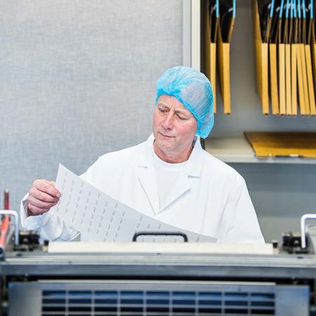 Factory worker checking printed wafer paper sheets